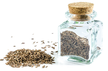 Dry caraway seeds in glass bottle and in a heap isolated on white background. Closeup macro shot.の写真素材