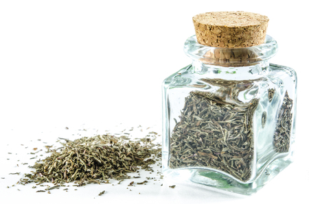 Dry thyme in glass bottle and in a heap isolated on white background. Closeup macro shot.の写真素材