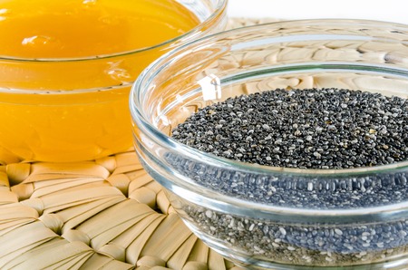 Chia seed and honey in a glass bowl on straw hot pad. Closeup shot. Healthy food concept.の写真素材