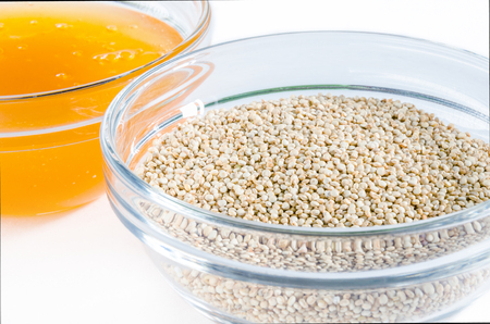 Quinoa and honey in a glass bowl isolated on white background. Closeup shot. Healthy food concept.の写真素材