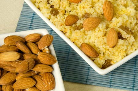 Plate with freshly cooked Moroccan couscous with almond on blue straw backgroundの写真素材