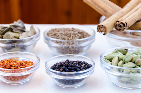 Different kind of indian spices such as cardamom, cumin, curry leaves,  cinnamon in glass bowls.の写真素材
