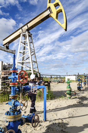 Woman engineer in the oilfield talking on the radio wearing white helmet and work clothes. Toned.の写真素材