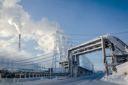High voltage power lines in the winter. Thermal power plant with smoke from the pipesの写真素材