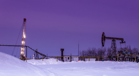 Pump jack, oil rig and pipeline  in the oilfield. Winter period. Oil and gas concept. Toned.の写真素材