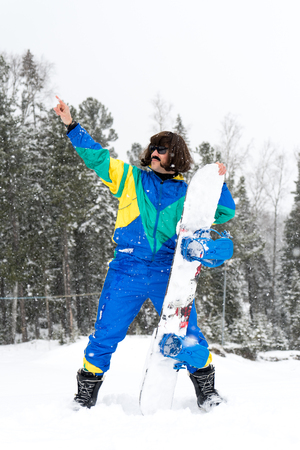 Vintage photo of young man snowboarder in the mountains. Retro style. 1980 concept.の写真素材