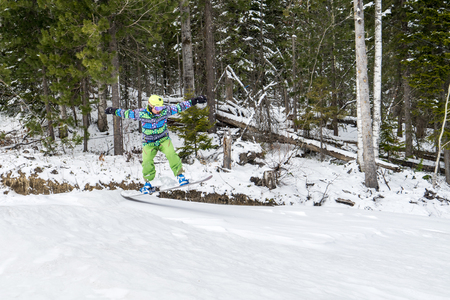 Snowboarder freerider jumping from a snow ramp on a background of forest and mountains.の写真素材