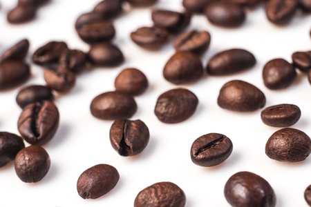 Brown roasted coffee beans lying on white background  selective focus の写真素材