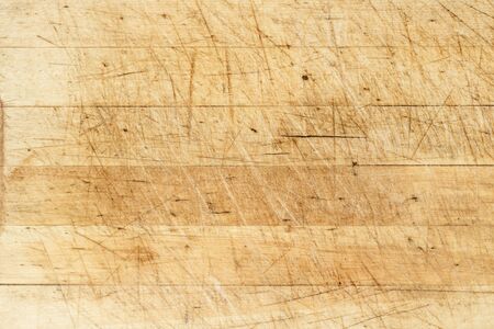 Old and used natural wooden cooking board with cuts