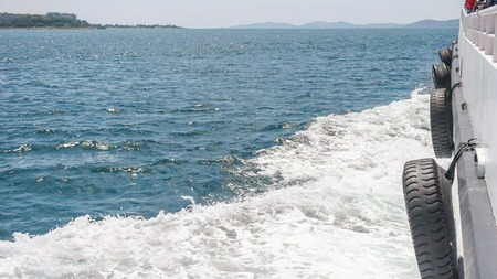 Side view, over the deck of the saling boat on the blue sea with water waves on the sideの写真素材