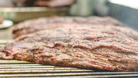 Line of sirloing meat being grilled during public food eventの写真素材