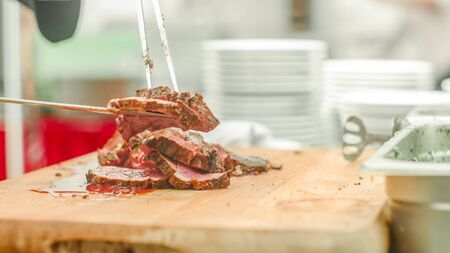 A chef slicing the meat and puting it on the plateの写真素材