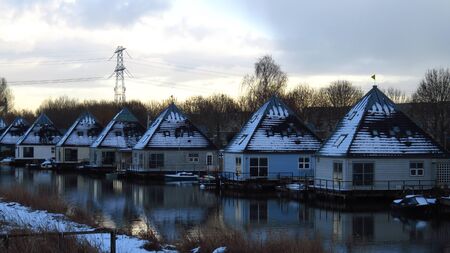 Beautiful Snow Covered Pyramid Shaped Houses on Canal During Winterの写真素材