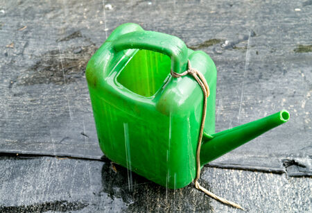 Drops of pouring rain on a green garden watering-canの写真素材