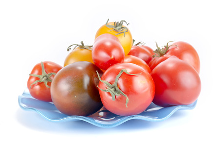 Tomatoes of different sorts on a blue saucer are isolated on a white backgroundの写真素材
