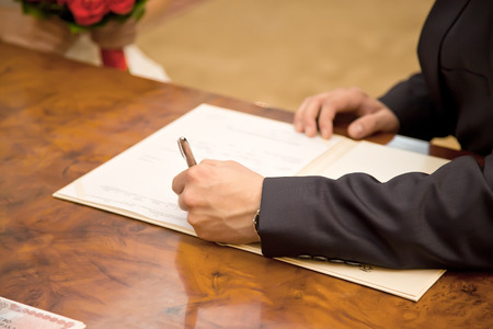 Marriage. Bridegroom puts his signature to the documentの写真素材