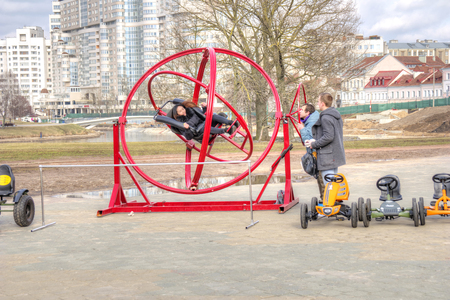 BELORUSSIA, MINSK - March 11.2017: The girl is spinning in a crazy attraction on a city streetのeditorial素材