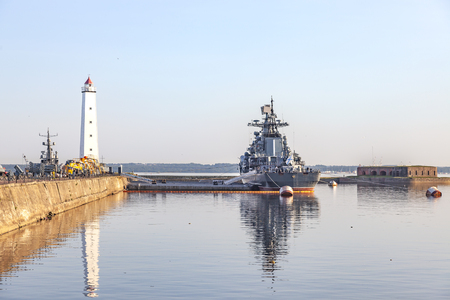 RUSSIA, KRONSHTADT - June 05.2019: Merchant's harbor. Antique wooden lighthouse and modern destroyerのeditorial素材
