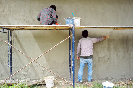 Workers installing bricklayer and plastering the cement texture on the wallの写真素材