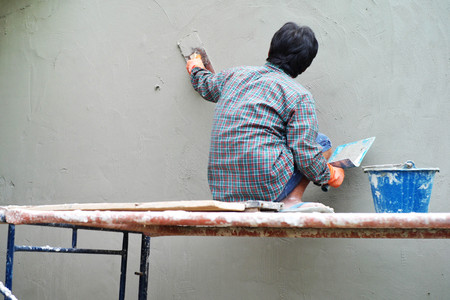 Workers installing bricklayer and plastering the cement texture on the wallの写真素材