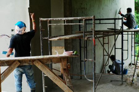 Workers installing bricklayer and plastering the cement texture on the wallの写真素材