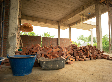 Pile of red brick stand by for installing to the wall at the house under construcrionの写真素材