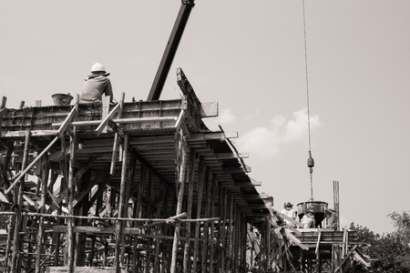 Monochrome of workers carrying the cement container to pour into the mold at the house under constrution. Teamwork and spirit conceptの写真素材