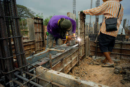 Workers welding the steel for supporting the mold of concrete structure at the construction siteの写真素材