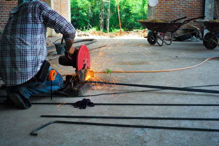 Worker cutting the reinforcement steel  by electrical cutting machine at the construction site. Sparkling light out of the steel cutting machine.の写真素材