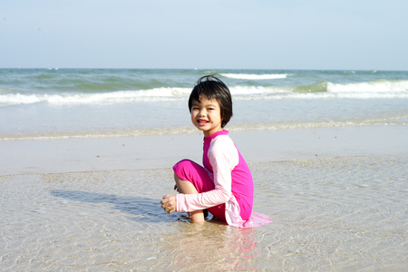 Asian girl plays on the beach and enjoys swimming in the sea in the sunshine day of summerの写真素材
