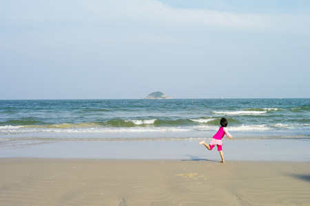 Asian girl plays on the beach and enjoys swimming in the sea in the sunshine day of summerの写真素材