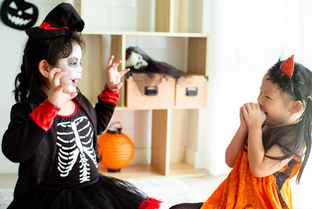 Portrait of two sisters in Halloween costume acting like a ghost frigthening expression to each other in Halloween festivalの写真素材
