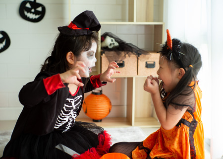 Portrait of two sisters in Halloween costume acting like a ghost frigthening expression to each other in Halloween festivalの写真素材