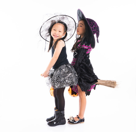 Portrait Asian girls in Halloween costume riding the broom together and holind the pumpkin with isolated backgroundの写真素材