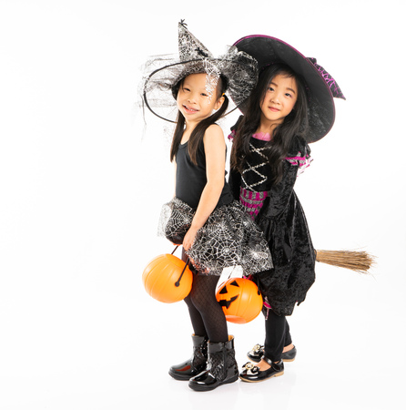 Portrait Asian girls in Halloween costume riding the broom together and holind the pumpkin with isolated backgroundの写真素材