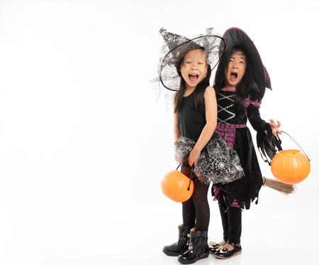 Portrait Asian girls in Halloween costume riding the broom together and holind the pumpkin with isolated backgroundの写真素材