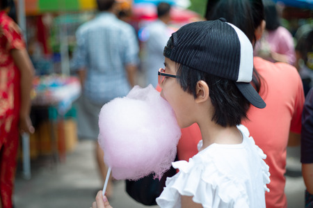 Portrait Asian girl eating the pink cotton candy at the outdoor marketの写真素材