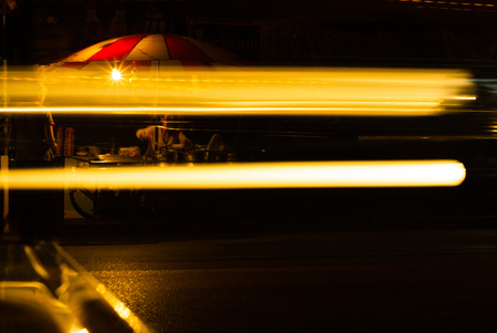 Defocused light trails with food stall in background at nightの写真素材