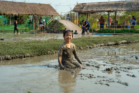 Portrait Asian wet girl enjoys plays in the mud pond and chases group of ducks in the farm.
