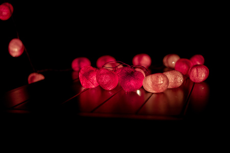 Closeup heart shape of led lights line puts on the wooden table decorated in the darkroomの写真素材