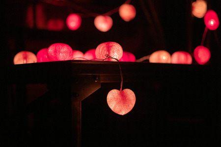 Closeup heart shape of led lights line puts on the wooden table decorated in the darkroomの写真素材