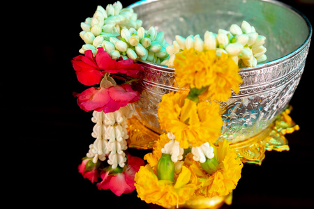 Isolated closeup flower garlands hanging on the edge of silver bowl with black backgroundの写真素材