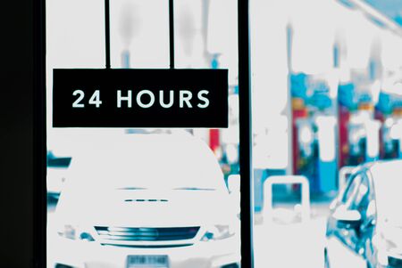 Selective focus on light box of working 24 hours of coffee shop. Co working space with blurred vehicles at oil station in backgroundの写真素材