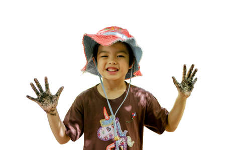 Portrait of Asian little girl enjoys playing in the farm. Smiling girl shows her dirty hands after molding the mud.の写真素材