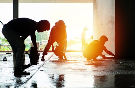 Silhouette group of workers build the cement floor in the house under construction.の写真素材
