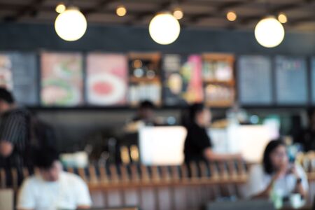 Defocused perpective of coffee shop with people. Blurred decorative lights inside co working space with bar in backgroundの写真素材