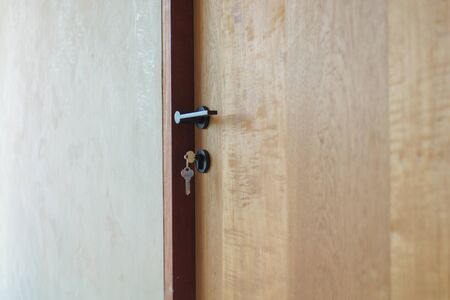 Selective focus on modern style of knob on wooden door with keys hanging on lockの写真素材