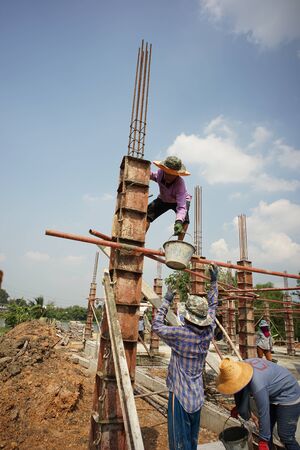 Ratchaburi, Thailand:March 1, 2018 - Group of worker build the foundation of house by pouring the mixed cement into the wooden model at the construction siteのeditorial素材