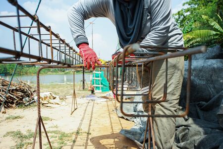 Worker doing the steelwork for reinforcement of the concrete structure at the construction siteの写真素材