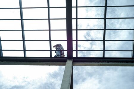 Workman waling along the steel structure of house's roof for survey at the construction siteの写真素材